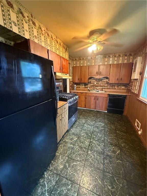 316 N 18th St, Lexington, MO 64067 - kitchen with black appliances, a ceiling fan, under cabinet range hood, light countertops, and brown cabinets