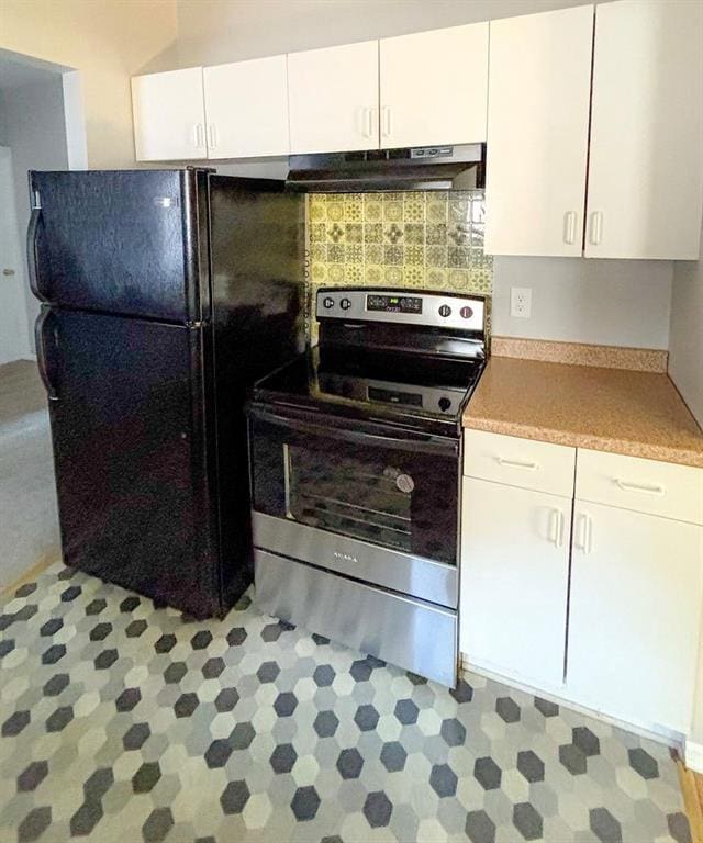 8106 Oak St, Kansas City, MO 64114 - kitchen featuring stainless steel electric range, under cabinet range hood, freestanding refrigerator, and white cabinets
