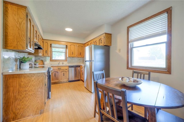 1101 Jeff Cir, Paola, KS 66071 - kitchen with stainless steel appliances, light countertops, a sink, brown cabinetry, and backsplash