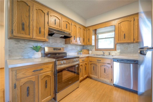 1101 Jeff Cir, Paola, KS 66071 - kitchen featuring stainless steel appliances, under cabinet range hood, light countertops, light wood finished floors, and a sink