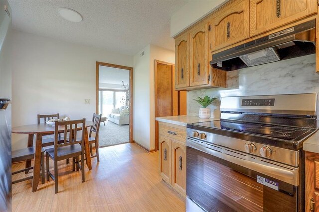 1101 Jeff Cir, Paola, KS 66071 - kitchen featuring electric stove, under cabinet range hood, light wood finished floors, a textured ceiling, and light countertops