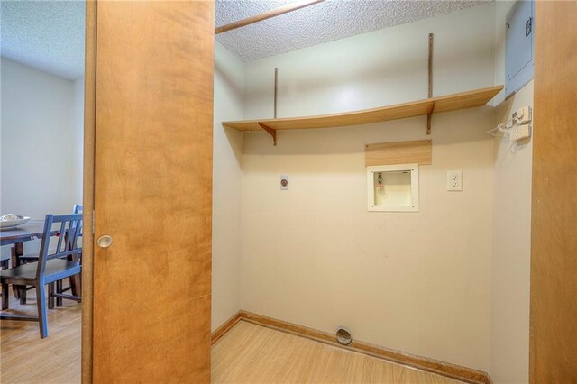 1101 Jeff Cir, Paola, KS 66071 - laundry area with hookup for an electric dryer, a textured ceiling, wood finished floors, and baseboards