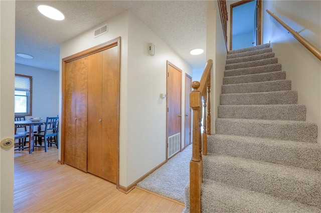 1101 Jeff Cir, Paola, KS 66071 - staircase featuring wood finished floors, a textured ceiling, and baseboards