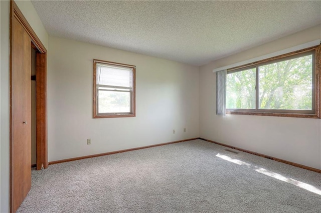 1101 Jeff Cir, Paola, KS 66071 - unfurnished bedroom featuring light colored carpet, multiple windows, a textured ceiling, and baseboards