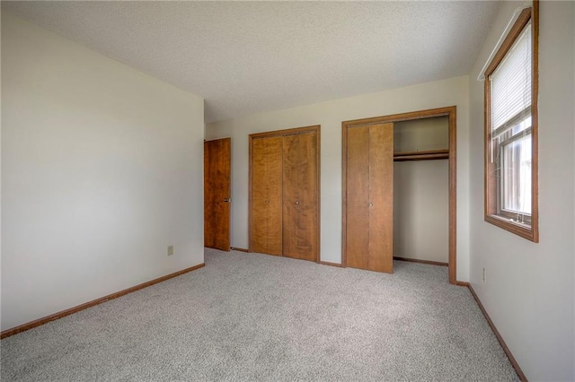 1101 Jeff Cir, Paola, KS 66071 - unfurnished bedroom featuring multiple windows, carpet flooring, multiple closets, and a textured ceiling