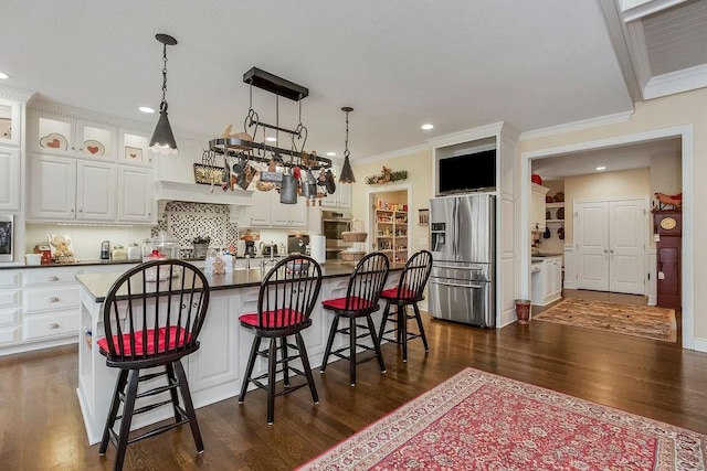 10309 S Oakcrest Ln, Olathe, KS 66061 - kitchen with appliances with stainless steel finishes, white cabinetry, dark wood finished floors, a kitchen breakfast bar, and ornamental molding
