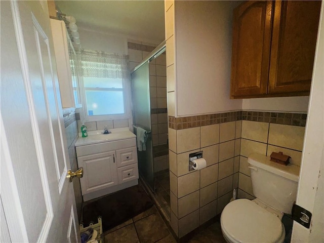 505 W 3rd Ave, Garnett, KS 66032 - bathroom with toilet, tile walls, a stall shower, tile patterned flooring, and vanity