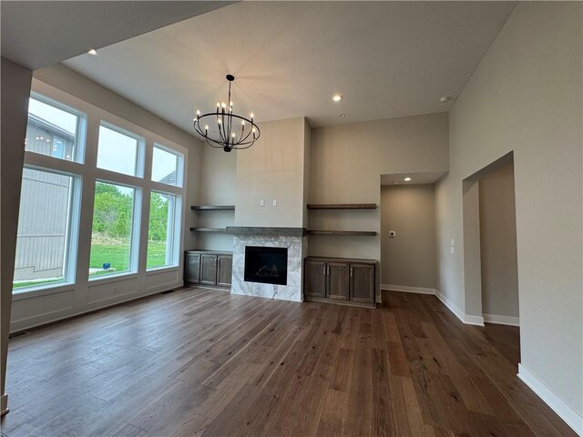 11494 S Longview Rd, Olathe, KS 66061 - unfurnished living room with dark wood-style floors, a chandelier, baseboards, a high ceiling, and a fireplace