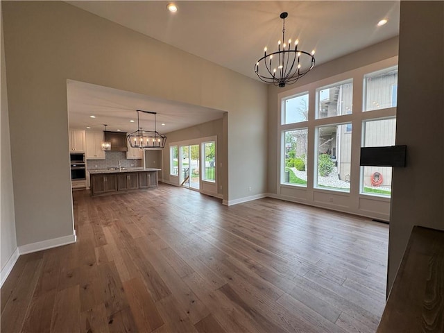 11494 S Longview Rd, Olathe, KS 66061 - unfurnished living room featuring a chandelier, wood finished floors, recessed lighting, baseboards, and a sink