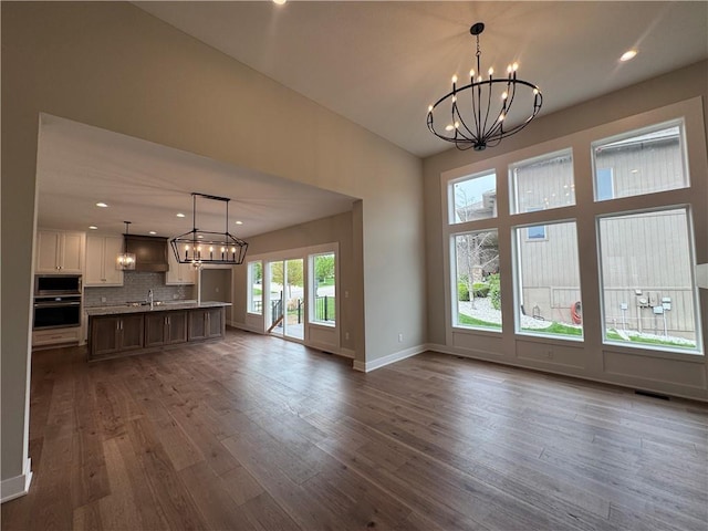 11494 S Longview Rd, Olathe, KS 66061 - unfurnished living room featuring a chandelier, dark wood-type flooring, baseboards, recessed lighting, and a sink