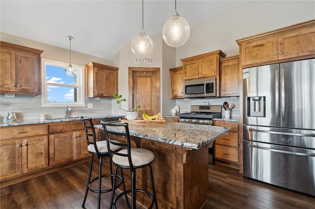 15700 NW 122nd St, Platte City, MO 64079 - kitchen with appliances with stainless steel finishes, brown cabinetry, a kitchen island, decorative backsplash, and dark wood-type flooring