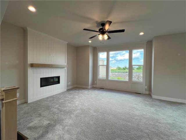 16977 S Mahaffie St, Olathe, KS 66062 - unfurnished living room featuring carpet flooring, ceiling fan, a large fireplace, baseboards, and recessed lighting