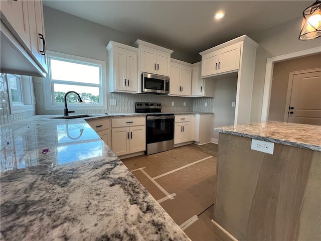 16977 S Mahaffie St, Olathe, KS 66062 - kitchen with appliances with stainless steel finishes, a sink, light stone counters, backsplash, and white cabinetry