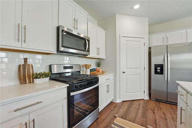 24810 178th Ct, Gardner, KS 66030 - kitchen featuring appliances with stainless steel finishes, wood finished floors, white cabinets, decorative backsplash, and light countertops
