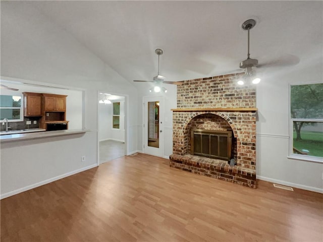 131 Brookridge St, Lansing, KS 66043 - unfurnished living room with a ceiling fan, wood finished floors, a fireplace, vaulted ceiling, and a sink