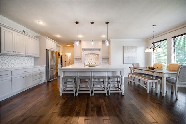 9101 W 158th St, Overland Park, KS 66221 - kitchen with freestanding refrigerator, light countertops, tasteful backsplash, dark wood-style flooring, and a kitchen bar