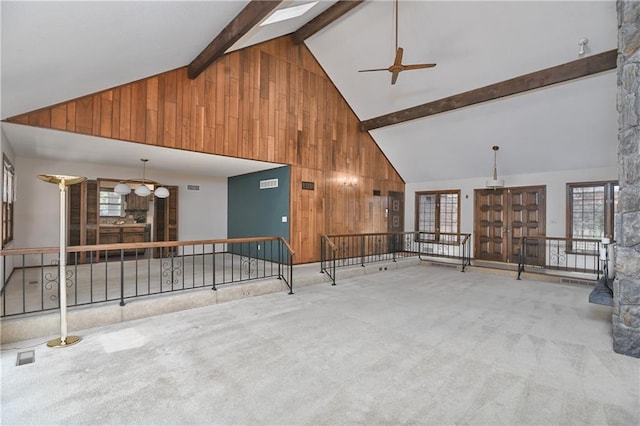 12614 Ensley Ln, Leawood, KS 66209 - unfurnished living room with wood walls, a ceiling fan, high vaulted ceiling, plenty of natural light, and carpet flooring
