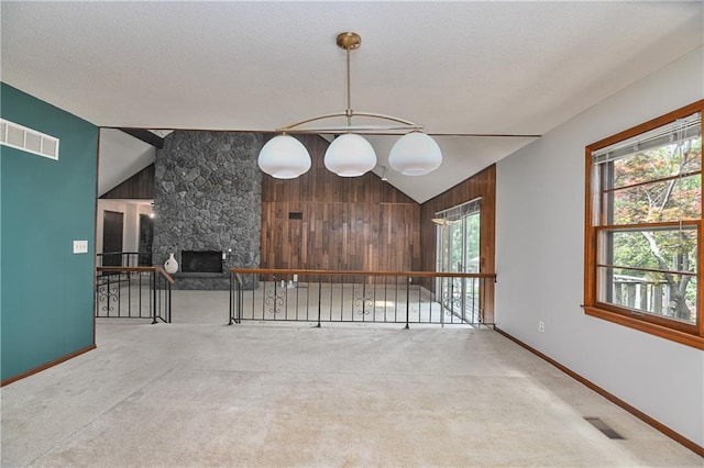 12614 Ensley Ln, Leawood, KS 66209 - carpeted spare room with vaulted ceiling, a stone fireplace, baseboards, and a textured ceiling