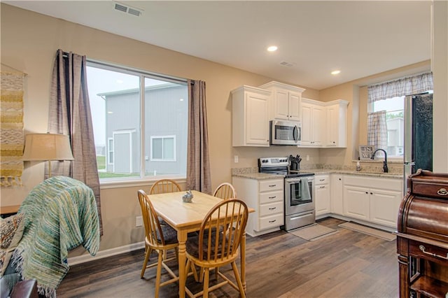 214 N Mcgee St, Tonganoxie, KS 66086 - kitchen with stainless steel appliances, dark wood-style floors, a sink, white cabinets, and light stone counters