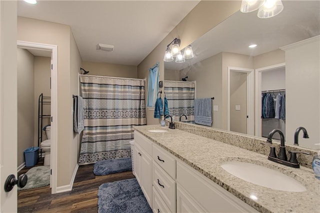 214 N Mcgee St, Tonganoxie, KS 66086 - bathroom with toilet, wood finished floors, double vanity, a shower with shower curtain, and baseboards