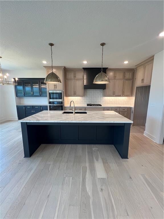 16311 Mustang St, Gardner, KS 66030 - kitchen with a sink, a spacious island, light wood-type flooring, tasteful backsplash, and stainless steel appliances