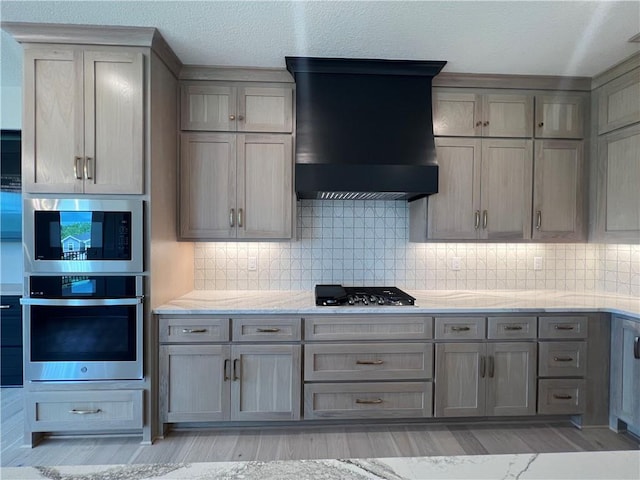 16311 Mustang St, Gardner, KS 66030 - kitchen featuring stainless steel appliances, wall chimney exhaust hood, gray cabinets, light wood-type flooring, and decorative backsplash