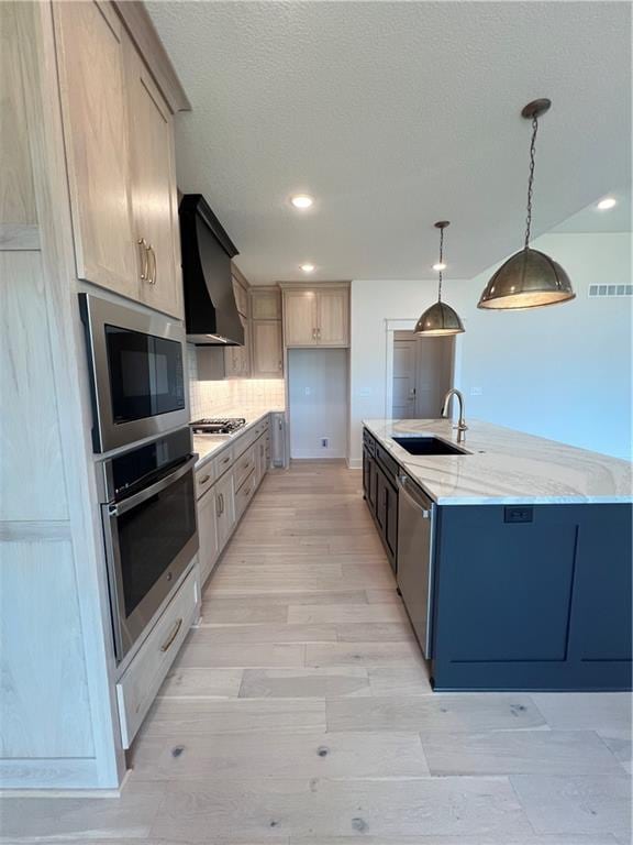 16311 Mustang St, Gardner, KS 66030 - kitchen with stainless steel appliances, a sink, wall chimney exhaust hood, light stone counters, and decorative backsplash