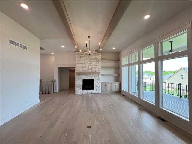 16311 Mustang St, Gardner, KS 66030 - unfurnished living room featuring beamed ceiling, light wood finished floors, a chandelier, baseboards, and a stone fireplace