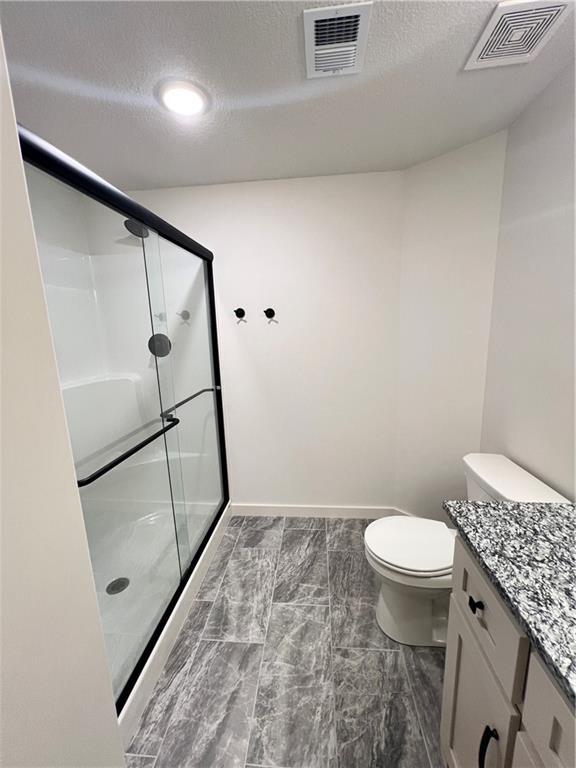 16311 Mustang St, Gardner, KS 66030 - bathroom with vanity, a shower stall, toilet, and a textured ceiling