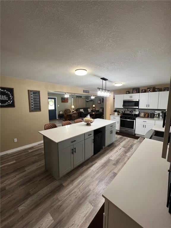 344 E 520th Ave, Pittsburg, KS 66762 - kitchen featuring stainless steel appliances, a center island, wood finished floors, a textured ceiling, and gray cabinets