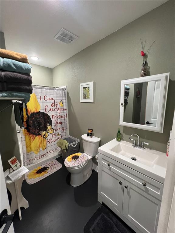 344 E 520th Ave, Pittsburg, KS 66762 - bathroom featuring vanity, toilet, curtained shower, and concrete floors