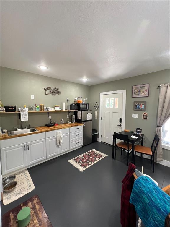 344 E 520th Ave, Pittsburg, KS 66762 - kitchen featuring white cabinets, a sink, black microwave, butcher block counters, and freestanding refrigerator