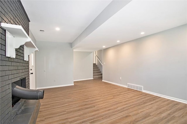 12309 Askew Dr, Grandview, MO 64030 - unfurnished living room with a brick fireplace, baseboards, stairs, light wood-style flooring, and recessed lighting