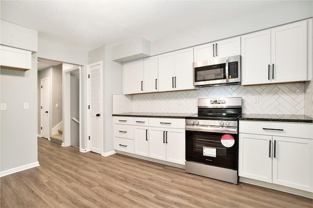 12309 Askew Dr, Grandview, MO 64030 - kitchen featuring stainless steel appliances, light wood-style floors, tasteful backsplash, white cabinets, and a textured ceiling