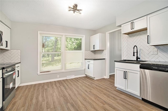 12309 Askew Dr, Grandview, MO 64030 - kitchen featuring stainless steel appliances, a sink, dark countertops, backsplash, and light wood-style floors
