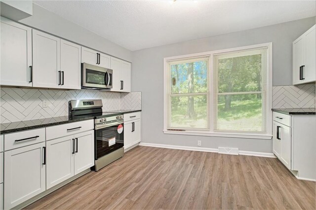 12309 Askew Dr, Grandview, MO 64030 - kitchen with appliances with stainless steel finishes, light wood-style flooring, tasteful backsplash, white cabinets, and baseboards