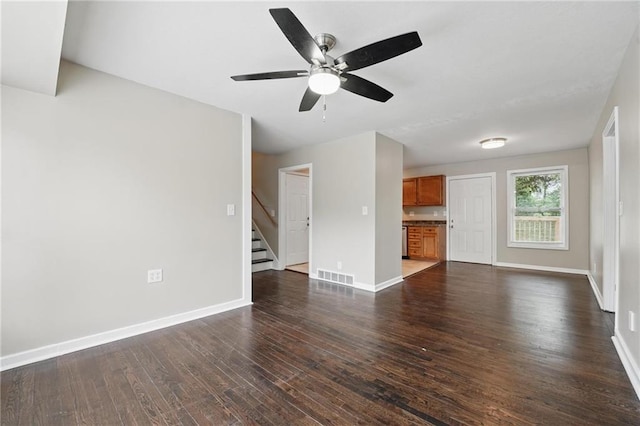 10217 Wheeling Ave, Kansas City, MO 64134 - unfurnished living room with stairs, dark wood-style flooring, baseboards, and a ceiling fan