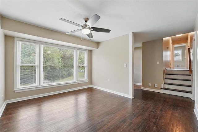 10217 Wheeling Ave, Kansas City, MO 64134 - empty room with dark wood finished floors, ceiling fan, baseboards, and stairway