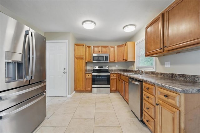 10217 Wheeling Ave, Kansas City, MO 64134 - kitchen with appliances with stainless steel finishes, a sink, dark countertops, light tile patterned floors, and brown cabinets
