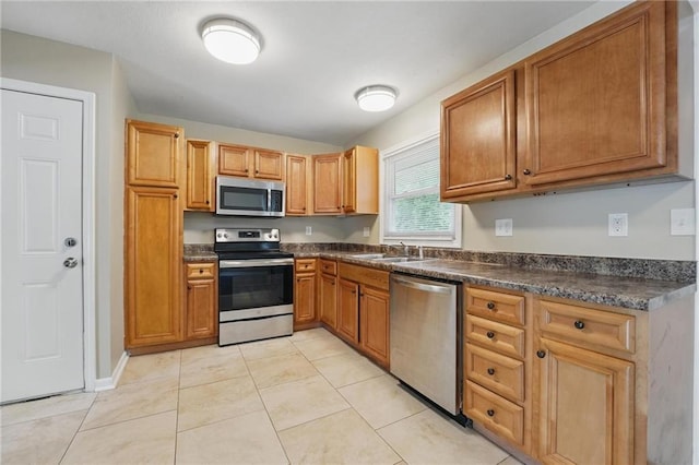 10217 Wheeling Ave, Kansas City, MO 64134 - kitchen with stainless steel appliances, a sink, dark countertops, and brown cabinetry