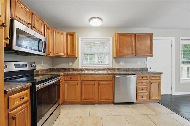 10217 Wheeling Ave, Kansas City, MO 64134 - kitchen featuring stainless steel appliances, a sink, dark countertops, and brown cabinetry