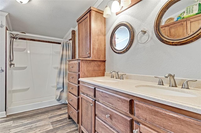 38686 Jingo Rd, Lacygne, KS 66040 - bathroom featuring wood finished floors, a shower with shower curtain, double vanity, a textured wall, and baseboards