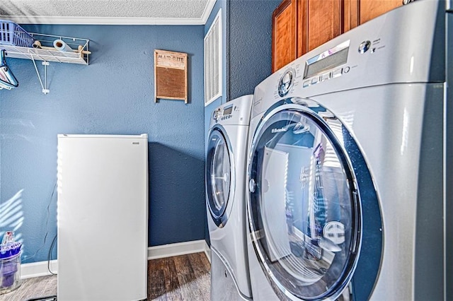 38686 Jingo Rd, Lacygne, KS 66040 - laundry area featuring cabinet space, separate washer and dryer, wood finished floors, a textured wall, and baseboards