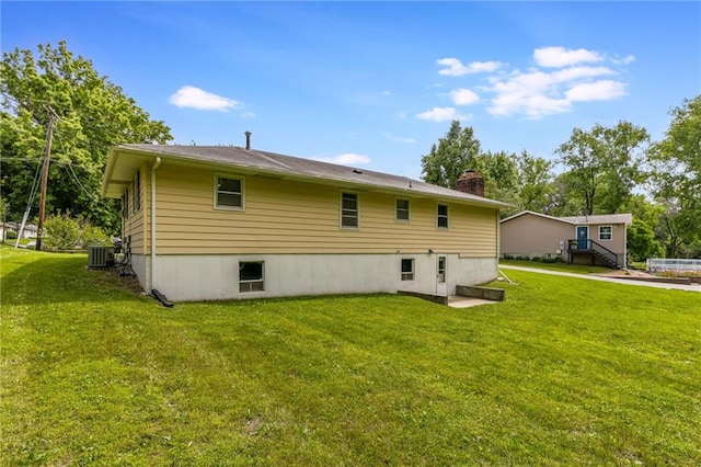 1221 Sunset St, Chillicothe, MO 64601 - rear view of house with central air condition unit, a chimney, and a lawn