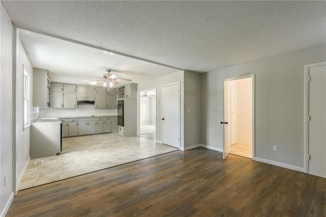 1221 Sunset St, Chillicothe, MO 64601 - unfurnished living room with ceiling fan, dark wood-style floors, a textured ceiling, a sink, and baseboards