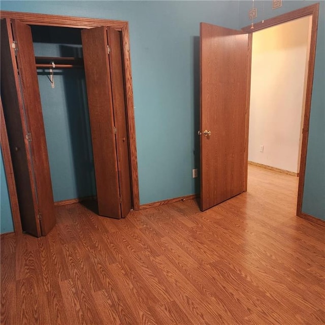 411 Briarwood Dr, Iola, KS 66749 - unfurnished bedroom with wood finished floors, a closet, and baseboards