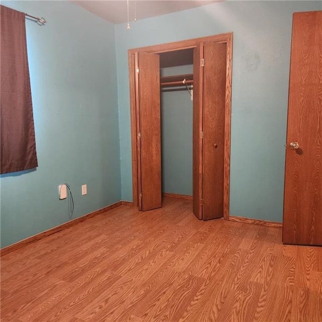 411 Briarwood Dr, Iola, KS 66749 - unfurnished bedroom featuring light wood-type flooring, a closet, and baseboards