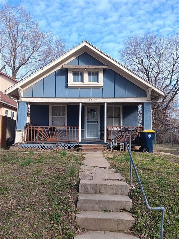 2539 Kensington Ave, Kansas City, MO 64127 - bungalow-style home featuring a porch, board and batten siding, and a front yard