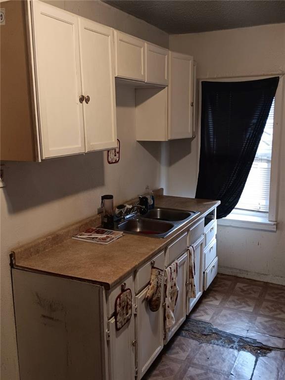 2539 Kensington Ave, Kansas City, MO 64127 - kitchen featuring a sink, white cabinets, and tile patterned floors