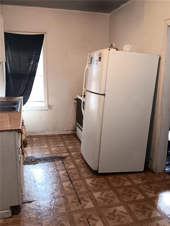 2539 Kensington Ave, Kansas City, MO 64127 - kitchen with freestanding refrigerator, light flooring, a sink, and range